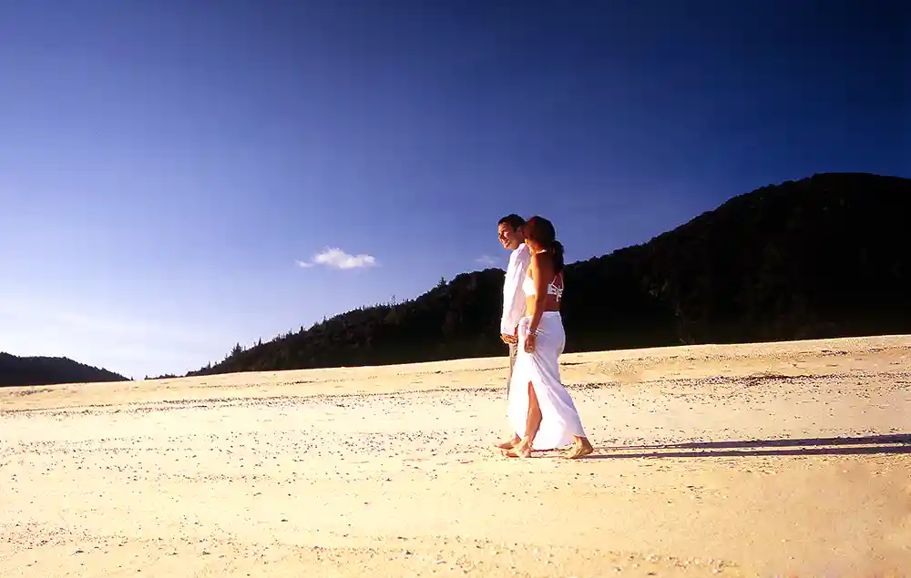 Couple walking hand in hand along deserted beach