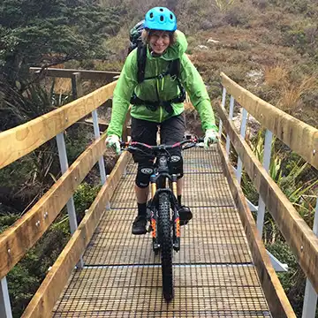 A Biker on the Heaphy Track crossing a bridge on the Gouland Downs