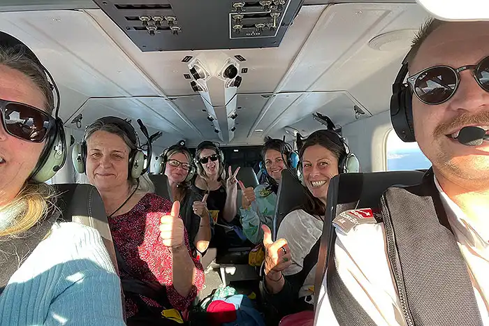 A group of happy passengers give the camera thumbs up in Golden Bay Air’s Airvan