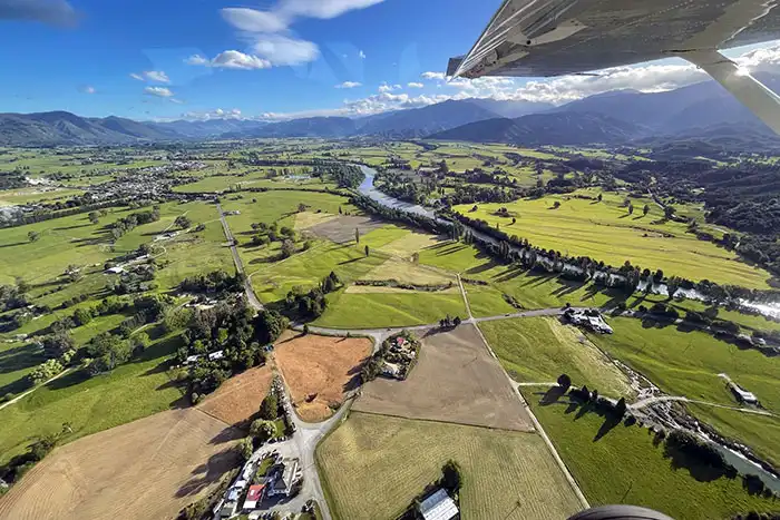 Aerial view of Takaka valley showing lush green farmland bordered by ranges with the Takaka River snaking past Takaka township