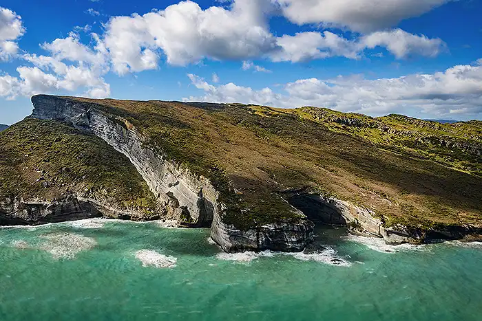 Dramatic limestone cliffs plunge into the sea from Mt Luna viewed from a west coast scenic flight